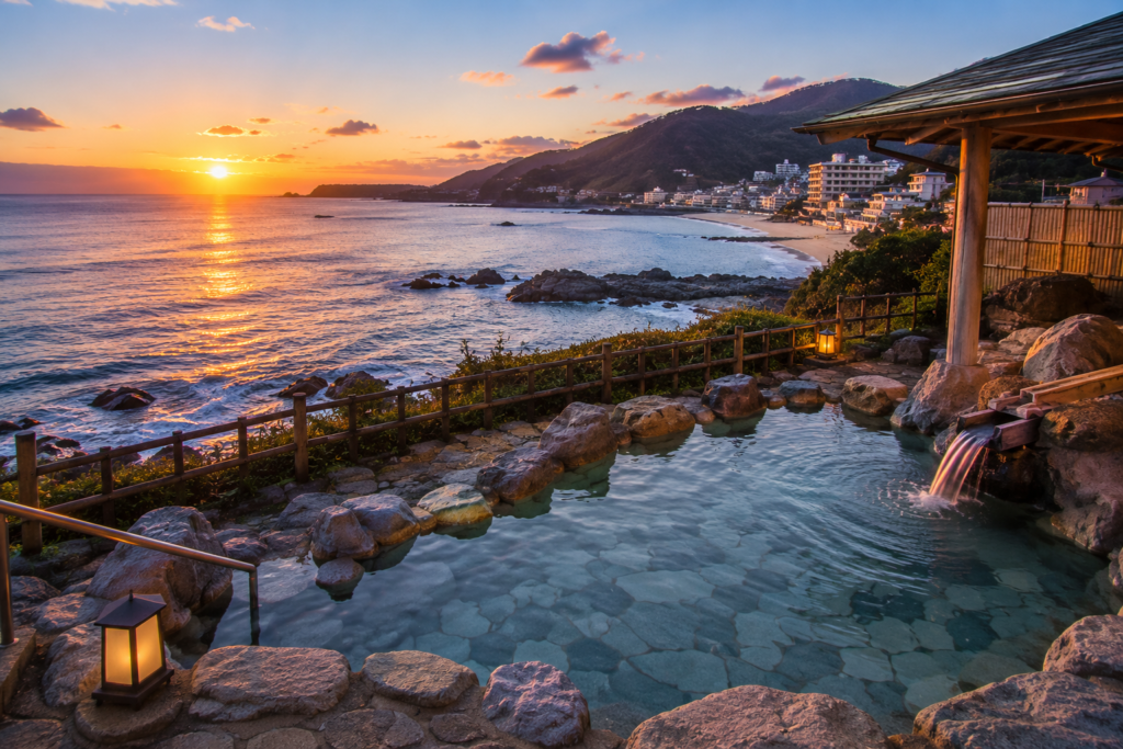 Seaside Japanese onsen overlooking the ocean and rocky coastline at sunset
